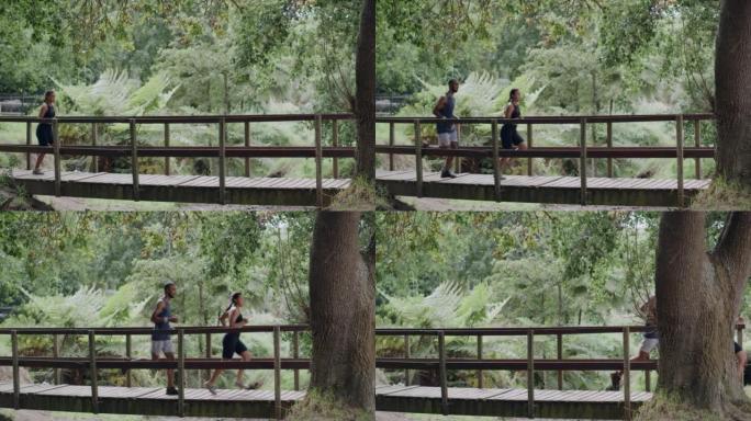 两名运动员在公园的行人天桥上奔跑。运动的年轻男女参加有氧运动。健身夫妇在户外比赛，让一起锻炼变得有趣