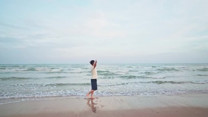 亚洲男子在海滩度假时散步并伸出手感到放松