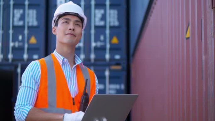 中国族裔工程师使用labtop计算机控制货物货运船的工业装载集装箱箱进行进出口。货物集装箱