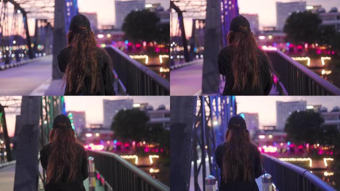 美丽的年轻亚洲少女晚上走在桥上