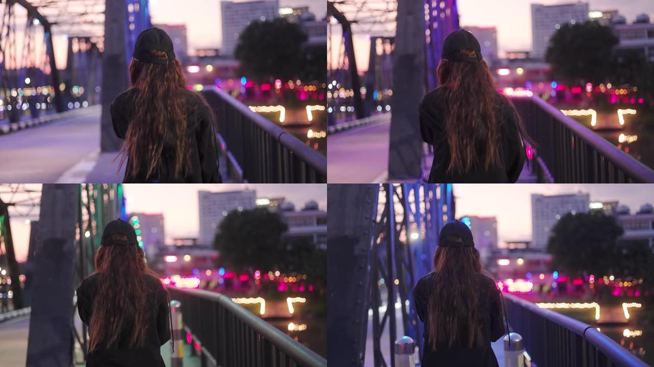美丽的年轻亚洲少女晚上走在桥上