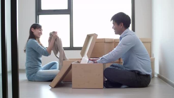 年轻的亚洲男女在新家中打开包装盒
