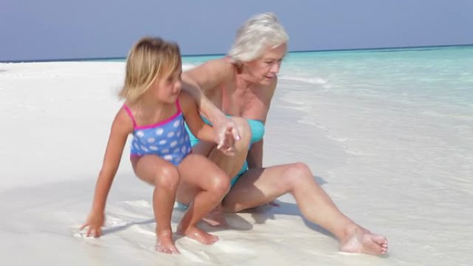 祖母和孙女坐在美丽的海滩上