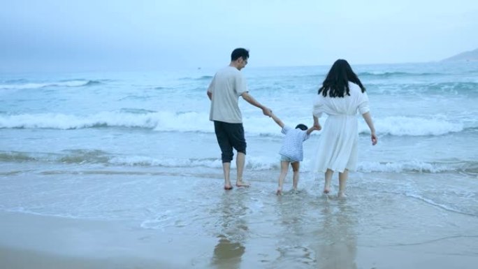 亚洲父母子在海边散步出海