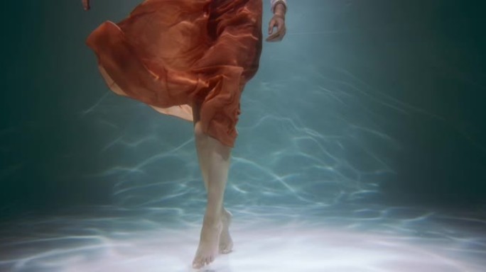 美丽健康的脚。水下电影，年轻女子的腿穿着时尚休闲棕色裙子慢动作