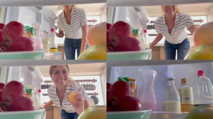 年轻漂亮的女人打开冰箱，拿水果吃早间小吃