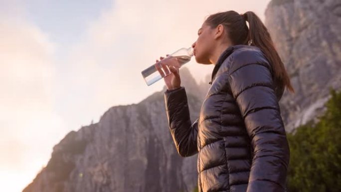 女游客从山上徒步旅行中休息，用水瓶喝水