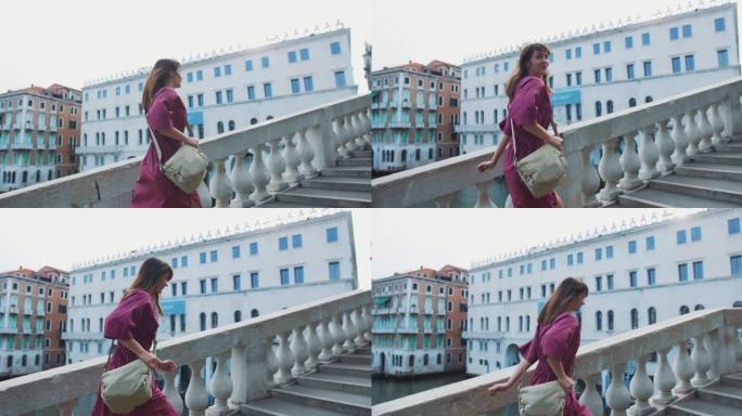 旅行癖。后视年轻快乐的黑发高加索旅行博客女人迅速走上威尼斯的里亚托大桥。