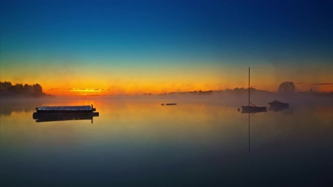 日出时漂浮在雾湖上的渔船