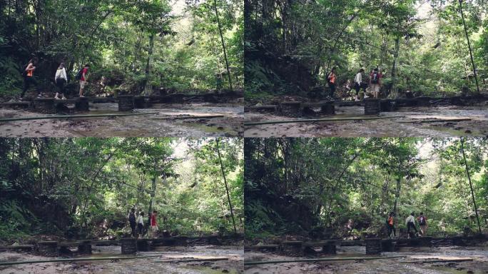 3位亚洲华人朋友在森林中漫步穿越河上的桥梁丛林徒步旅行