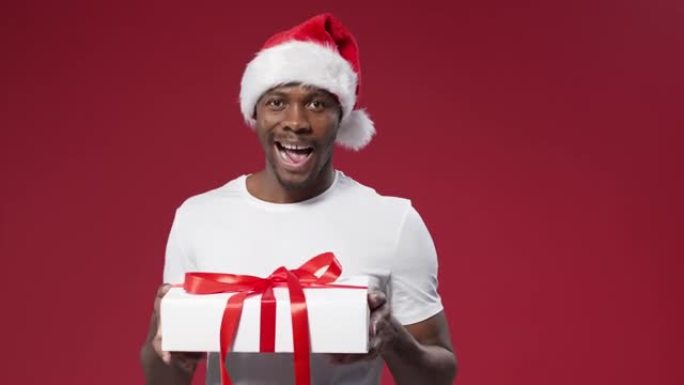 一个戴着圣诞帽的黑皮肤微笑的男人转过身，从四面八方看着礼品盒