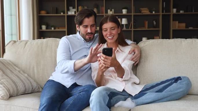 年轻夫妇在智能手机上阅读好消息感到喜出望外