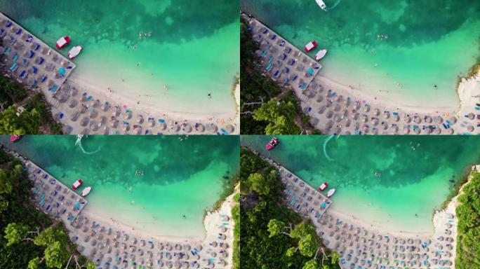 空中俯视壮丽的海滩，有清澈的蓝色水和白色的沙子。人们在度假时享受日光浴和游泳，在海上度过暑假。阿尔巴