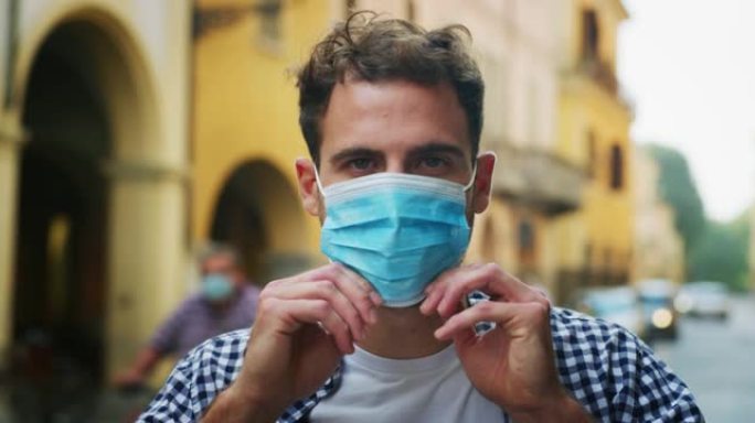 在市中心，一名年轻男子戴着医用口罩保护自己免受疾病侵袭。污染、环境、保护、病毒传播、安全、隔离、co
