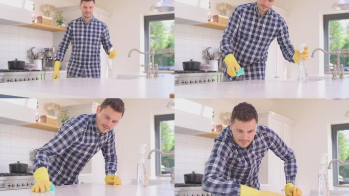 男人在家做家务戴着橡胶手套用喷雾和布清洁厨房柜台