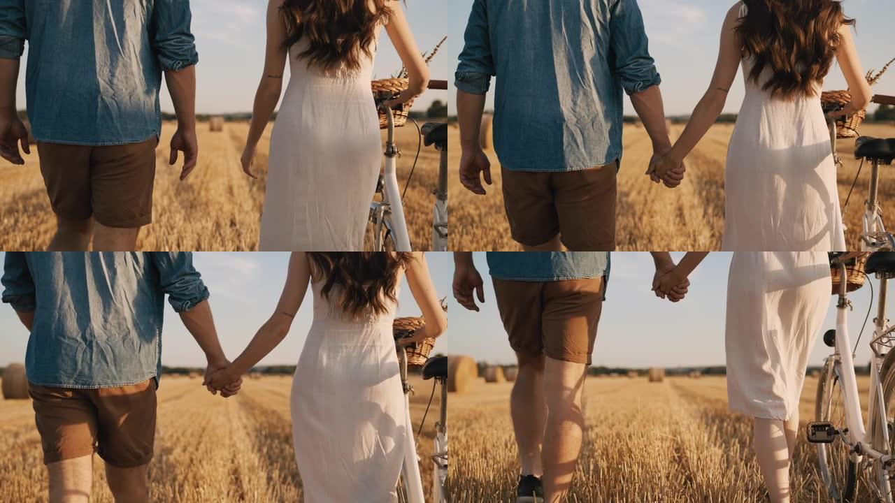 中等慢动作拍摄成年夫妇手牵着手走在收获的田地上，在阳光明媚的日子里骑自行车
