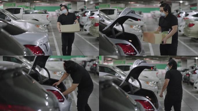 亚洲男子携带纸盒与农产品走向汽车