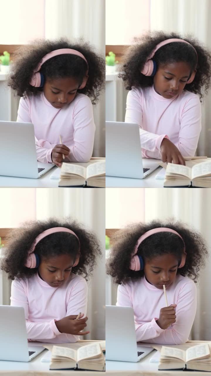 戴着耳机的非洲小女孩在家学习使用笔记本电脑