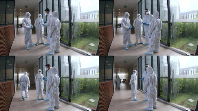 男医生在新型冠状病毒肺炎大流行期间将任务分配给他的团队，他们都穿着生物安全服和元素