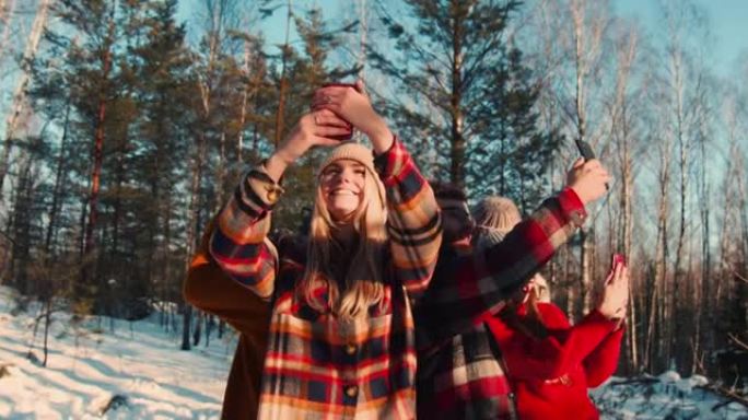 自私的文化。摄像机在快乐的多民族朋友周围移动，在阳光明媚的冬天森林慢动作中自拍。