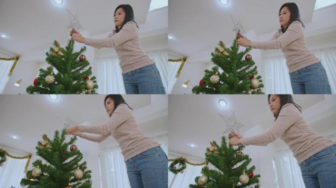 女人在圣诞树上悬挂着闪闪发光的星星装饰