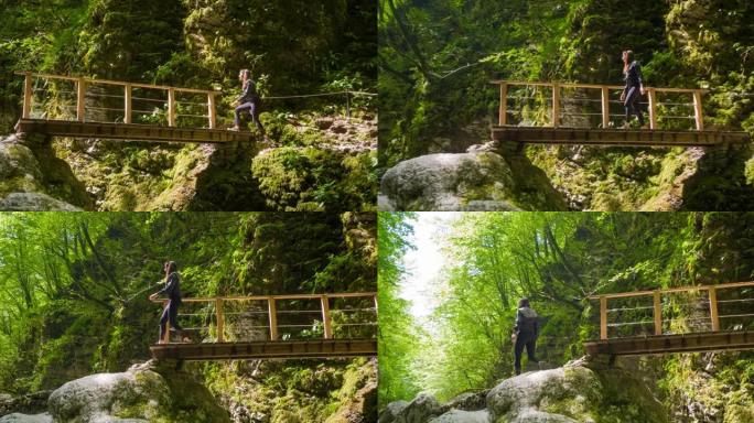 健康的女人在大自然中徒步旅行，在雄伟的绿色峡谷的一条小溪上过桥