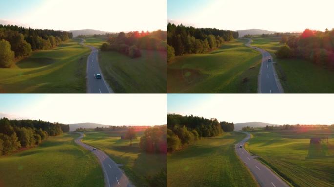 空中: 秋天日落时，两辆迎面驶来的汽车沿着沥青乡间小路行驶
