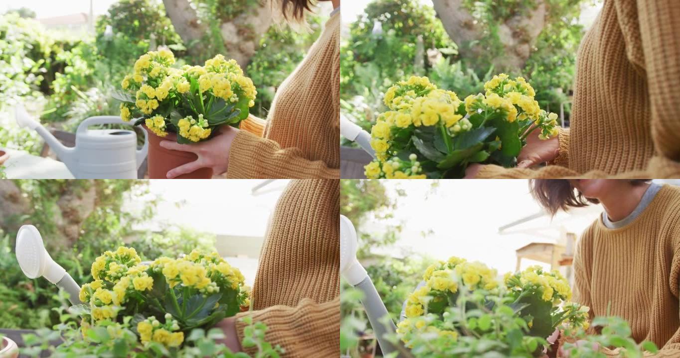 微笑的白人妇女在阳光明媚的花园里种着黄色的花朵