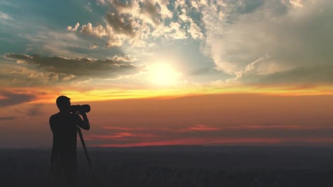 男人在美丽的日落背景下使用带三脚架的相机