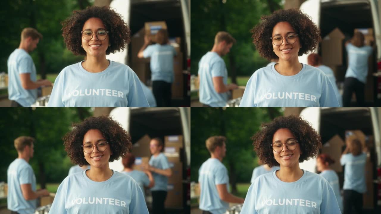 一位快乐乐于助人的黑人女性志愿者的肖像。年轻的多民族拉丁人，非洲裔头发，戴着眼镜，微笑着，摆姿势拍照