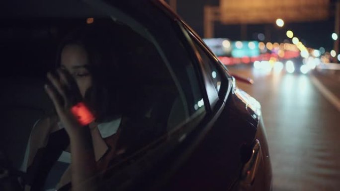 女人在开车穿越城市时使用电话晚上回家