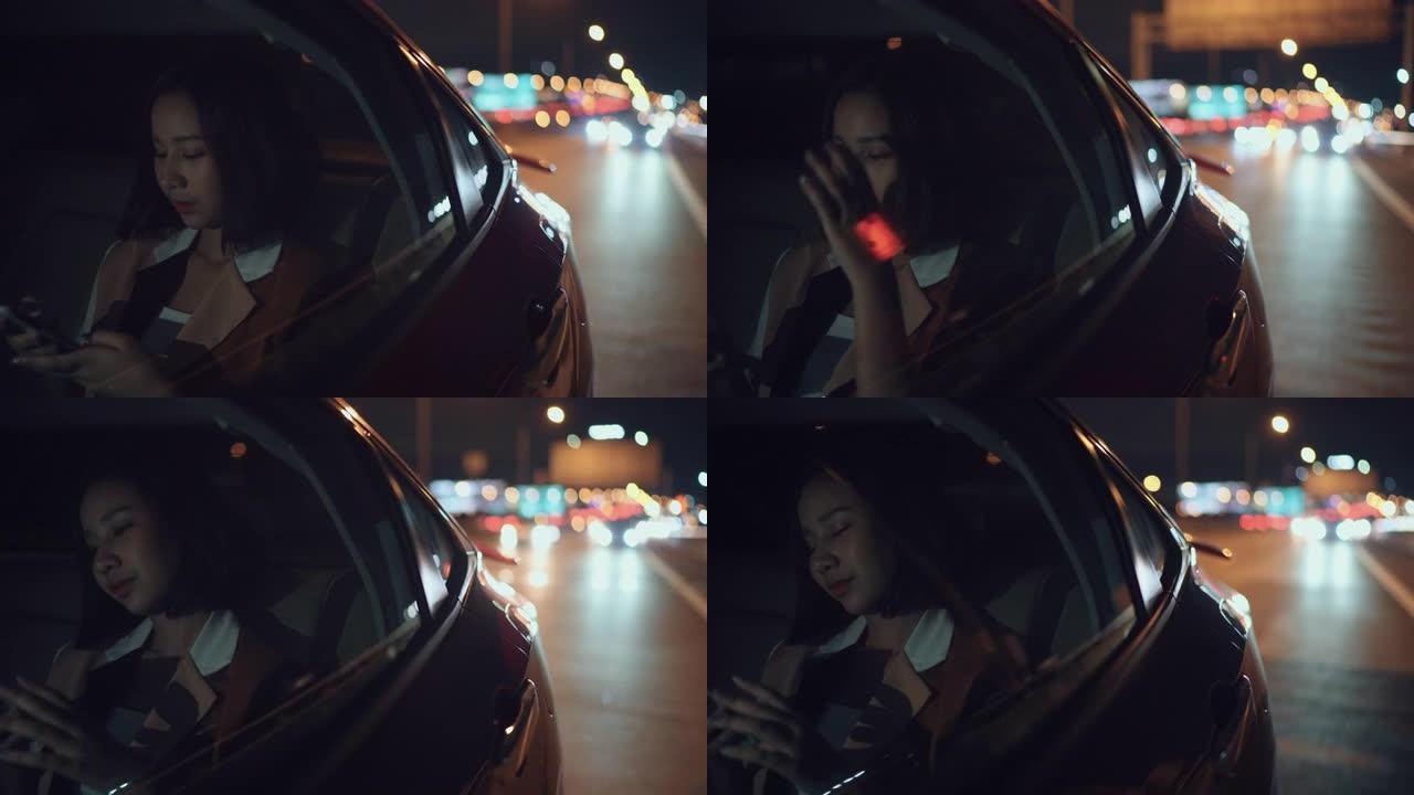 女人在开车穿越城市时使用电话晚上回家