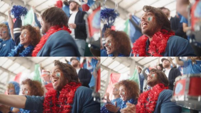 体育馆足球比赛: 双种族夫妇的肖像与意大利国旗彩绘的面孔欢呼队获胜，击败手鼓。人群庆祝进球，冠军胜利