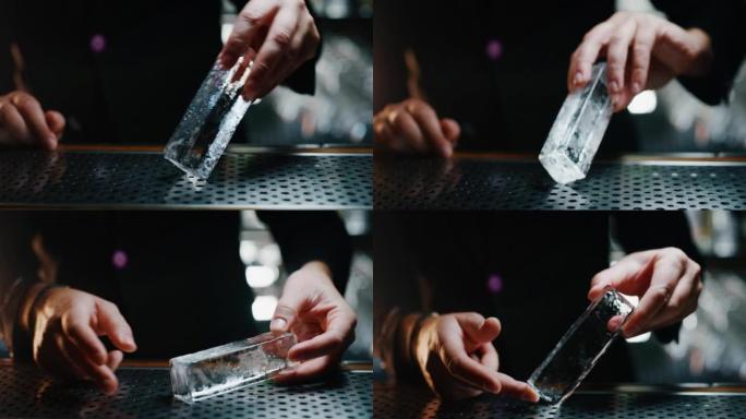 调酒师的特写镜头正在切割专业的水晶持久冰块，以便在酒吧或迪斯科俱乐部为顾客准备精英酒精鸡尾酒。