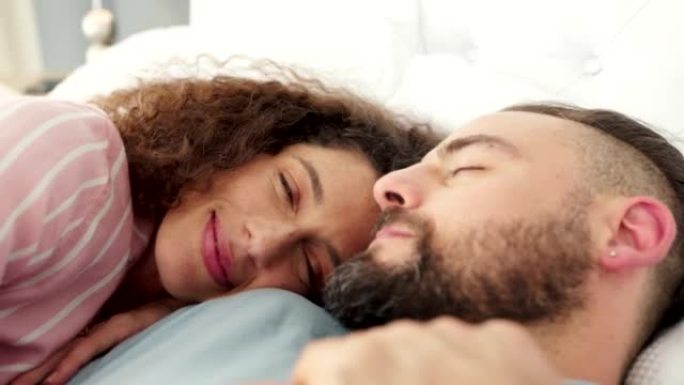 在一个周末的早晨，与一对夫妇一起在他们家卧室的床上睡觉，爱与放松。睡觉，快乐和微笑的男人和女人在他们