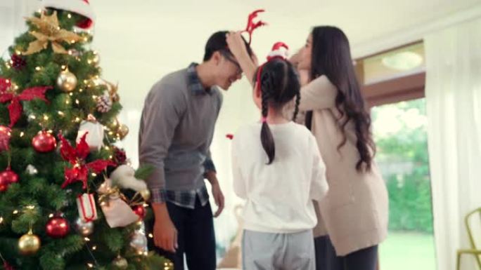 4K UHD平移亚洲幸福家庭装饰圣诞树与装饰品一起为节日快乐冬天做准备。