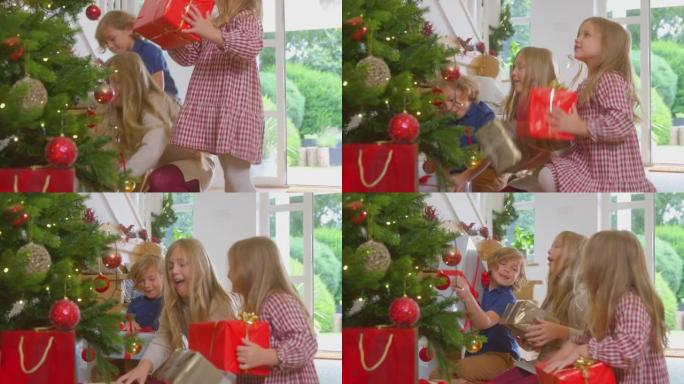 三个兴奋的孩子在楼下奔跑，在家里的圣诞树下摇晃礼物