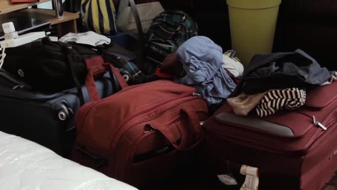 凌乱的房间，衣服，手袋和行李被遗弃或存放在地板上。