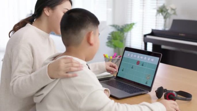家长在电脑笔记本电脑上教亚洲孩子不插电编码。