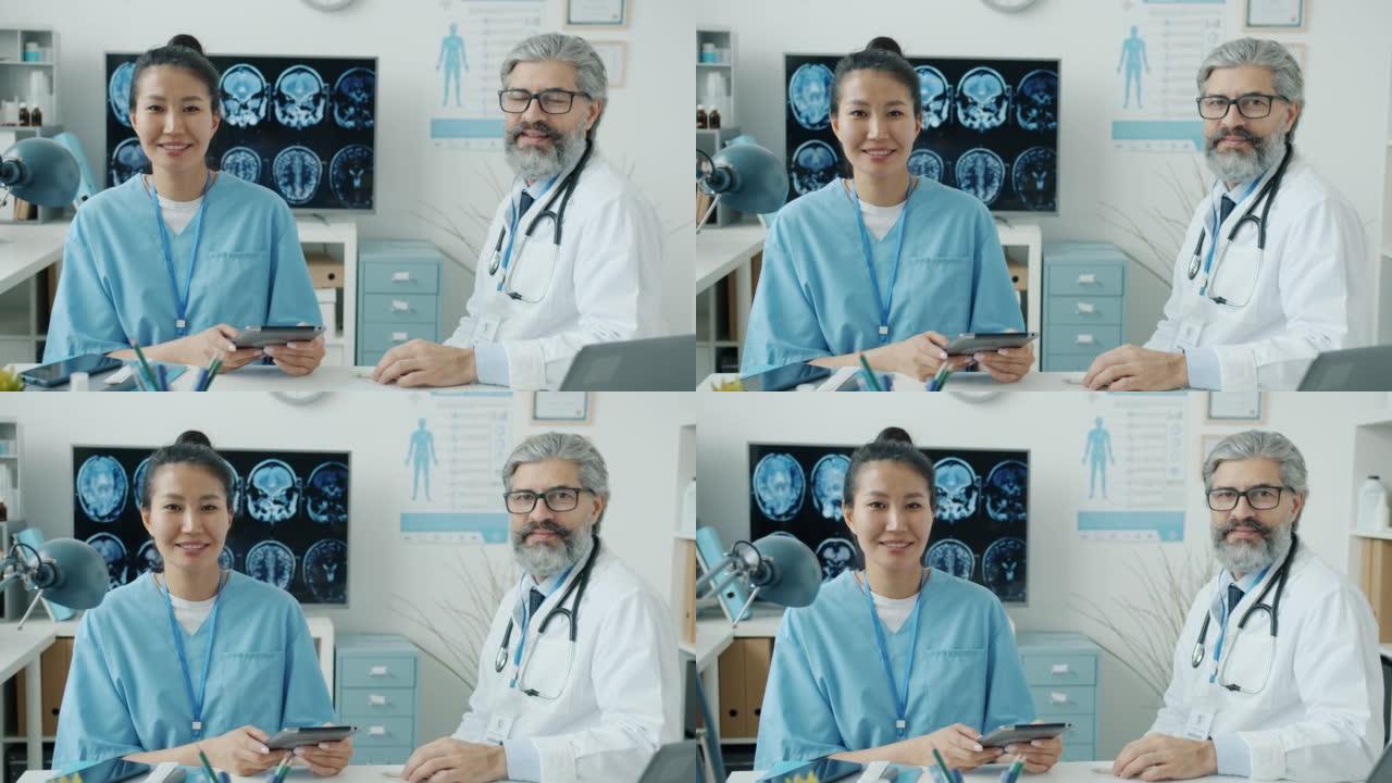 医生和护士坐在医院的工作场所微笑着看着相机