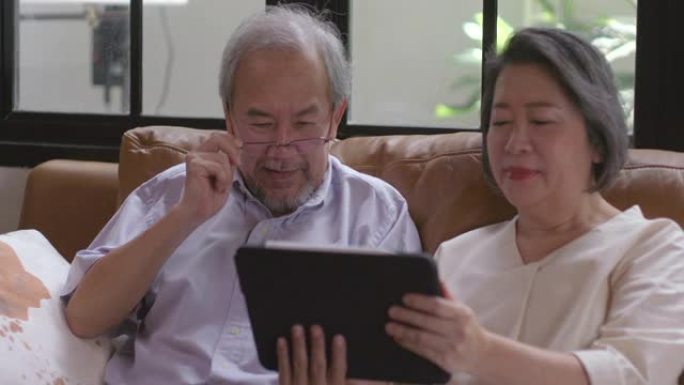 祖父和祖母坐在工作中在家中使用平板电脑，这是老年人使用现代技术的学习。在没有病毒的检疫期间。