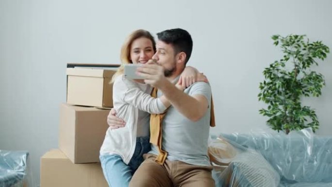 幸福夫妻的慢动作在智能手机视频通话中聊天，显示带盒子的新公寓