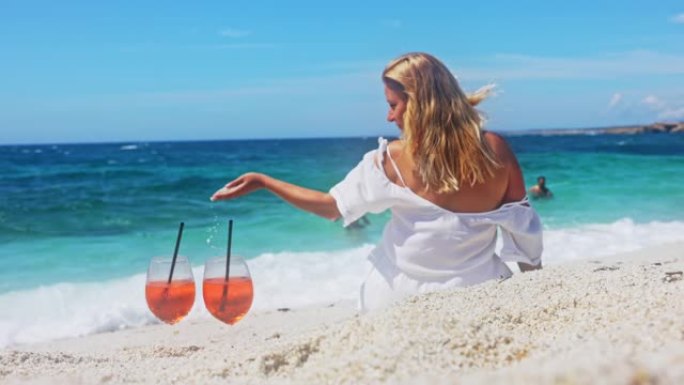 一个女人在海滩上喝酒的慢动作视图。