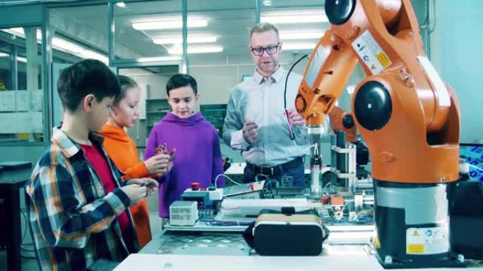 男工程师正在现代课堂上向孩子们解释机器人技术。