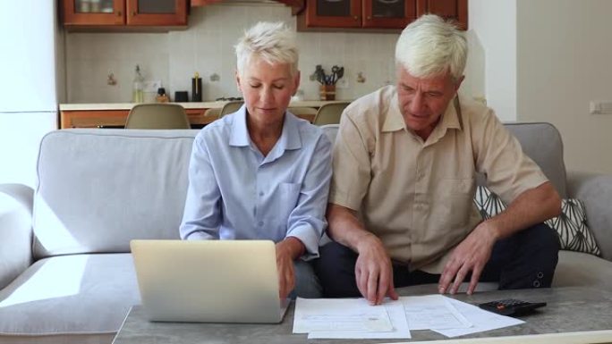 老年夫妇讨论家庭预算，审查家庭账单