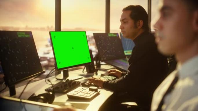 带耳机的男性空中交通管制员可在机场塔楼的绿屏模拟计算机上工作。办公室带有带有导航屏幕的显示器，团队的