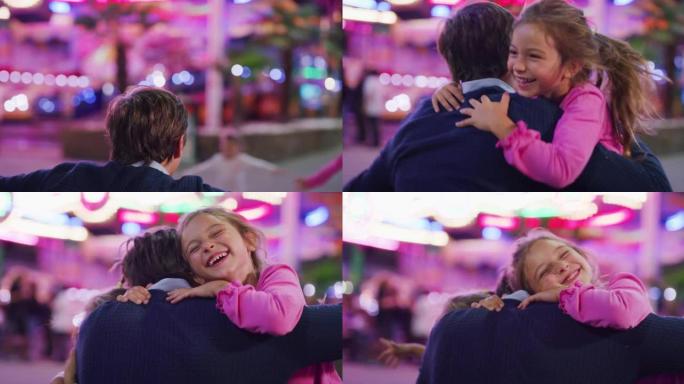 一个快乐微笑的女儿的真实特写镜头正在奔跑，给父亲一个情感的拥抱和亲吻，同时晚上在游乐园里与露娜公园的