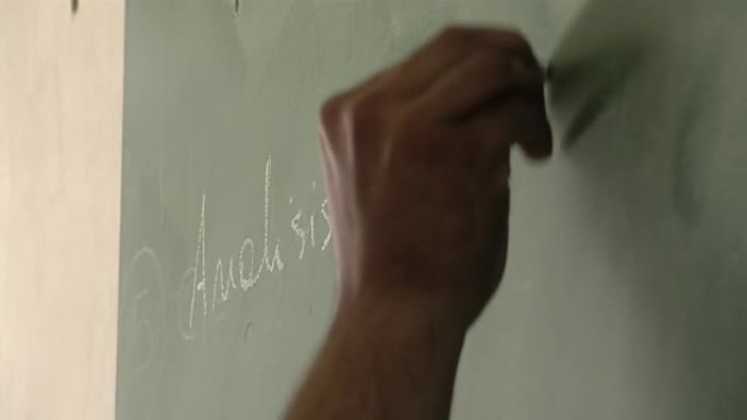 在阿根廷监狱为囚犯举行的教育课上，一名男老师在绿色黑板上写字。特写。
