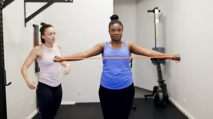 女人在健身房与健身教练一起锻炼