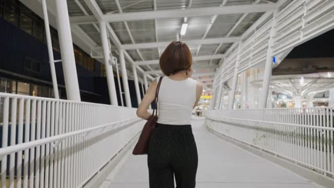 后视美丽的亚洲女人戴着防护面罩走路和使用智能手机，新的正常概念，人们新型冠状病毒肺炎后的生活方式